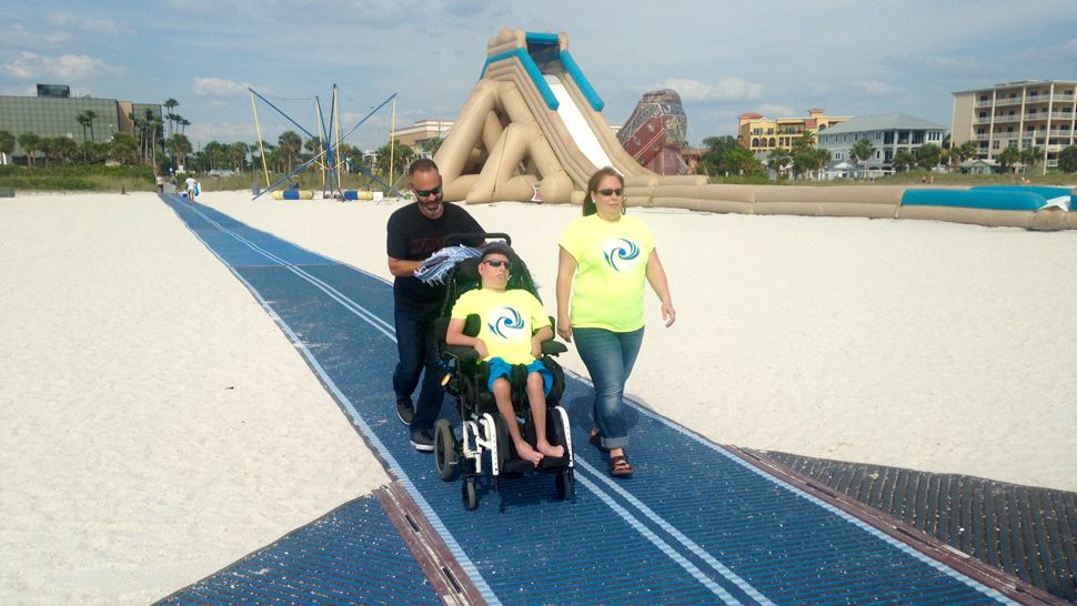 Okini and Samantha Hernandez accompany their son, Jimmy Ortiz, 15, in his wheelchair on Treasure Island's new MobiMat RecPath, Wednesday, May 9, 2018. (Josh Rojas, staff)