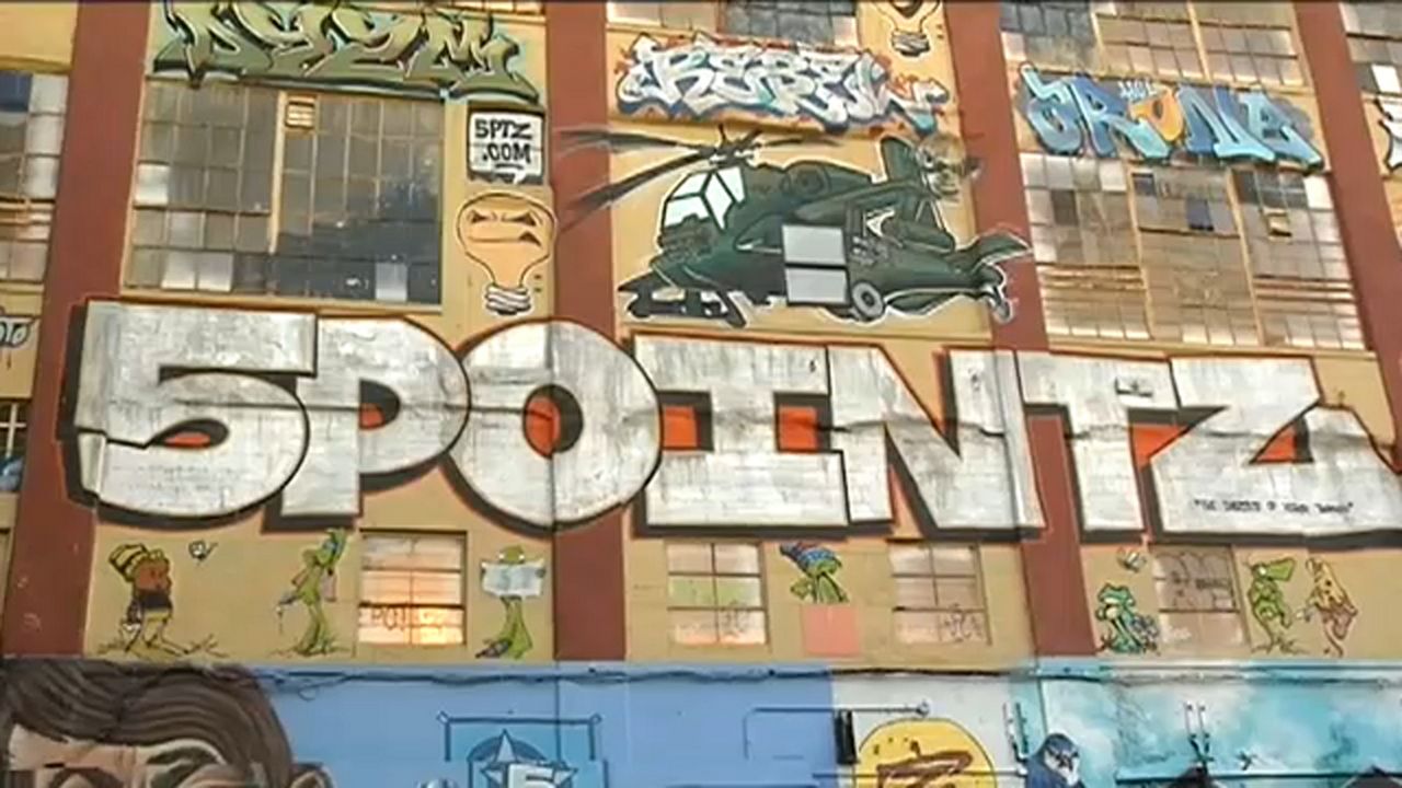 Graffiti art plastered on a building. White block text on the building says "5POINTZ."