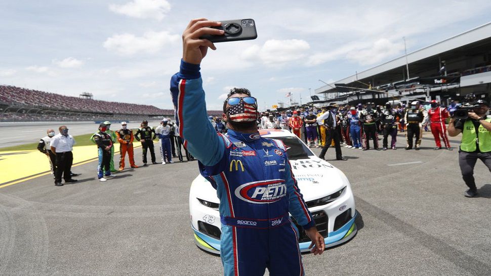 NASCAR driver Bubba Wallace takes a selfie with himself and other drivers who pushed his car to the front of pit road of the Talladega Superspeedway prior to the start of Monday's Cup Series race.  (AP Photo/John Bazemore)