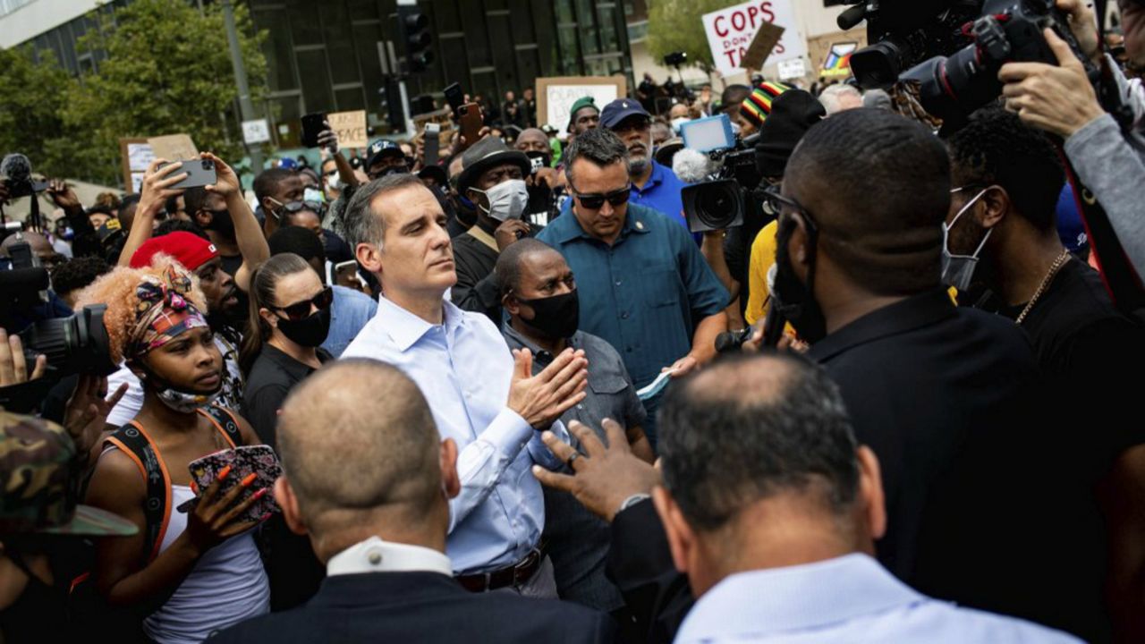 Los Angeles Mayor Eric Garcetti joins pastors and marchers outside LAPD Headquarters during a demonstration demanding justice for George Floyd, Tuesday, June 2, 2020 in Los Angeles, Floyd, a black man, died after being restrained by Minneapolis police officers on May 25. (Sarah Reingewirtz/The Orange County Register via AP)