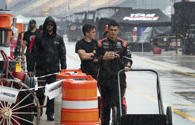 Rain falls on crew members before the NASCAR Xfinity series race in Brooklyn, Michigan.  (AP Photo/Carlos Osorio)