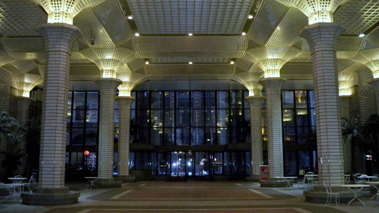 The atrium of 60 Wall Street is pictured, with tall gray stone columns that resemble palm trees.