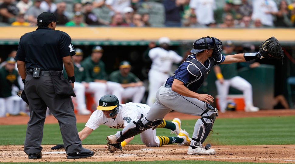 Tampa Bay Rays catcher Rob Brantly, right, waits for the throw as Oakland Athletics' Tyler Nevin scored on Darell Hernaiz's double during the second inning of a baseball game Thursday, Aug. 22, 2024, in Oakland, Calif. (AP Photo/Godofredo A. Vásquez)