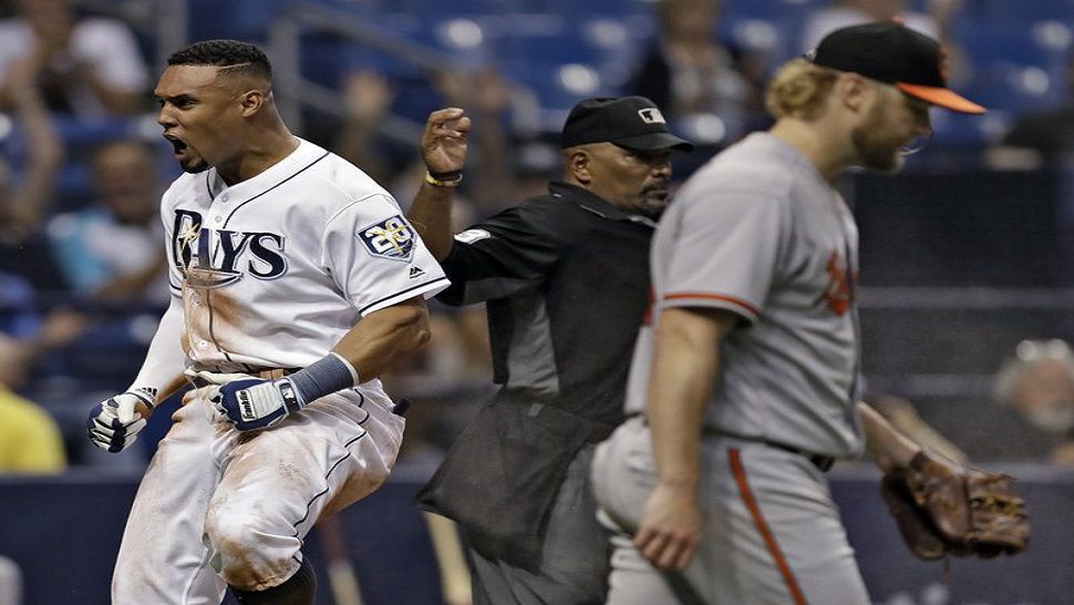 Tampa Bay Rays’ Carlos Gomez, left, celebrates after scoring on a sacrifice fly by Michael Perez off Baltimore Orioles starting pitcher Andrew Cashner, right, during the seventh inning of a baseball game Wednesday, Aug. 8, 2018, in St. Petersburg, Fla. Making the call is home plate umpire Laz Diaz. (AP Photo/Chris O’Meara)
