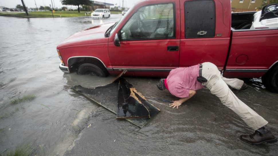 Felipe Morales works on getting his truck out of a ditch filled with high water during a rain storm stemming from rain bands spawned by Tropical Storm Imelda on Tuesday, Sept. 17, 2019, in Houston. He was able to get help when a man with a truck helped pull him from the ditch. (Brett Coomer/Houston Chronicle via AP)