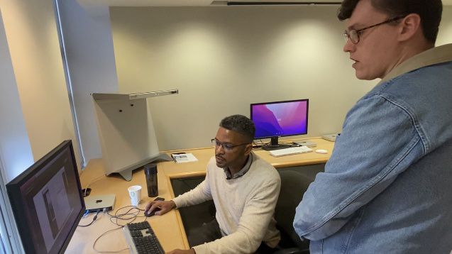 Two persons work on computer.