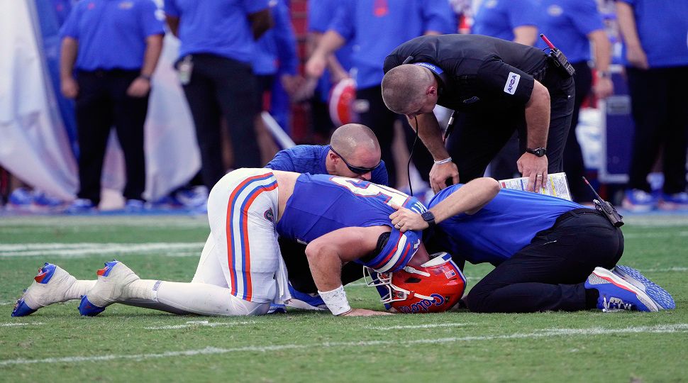 Florida quarterback Graham Mertz, front left, is looked at by head coach Billy Napier, top right, and other team personnel after he was injured during the second half of an NCAA college football game against Miami, Saturday, Aug. 31, 2024, in Gainesville, Fla. (AP Photo/John Raoux)