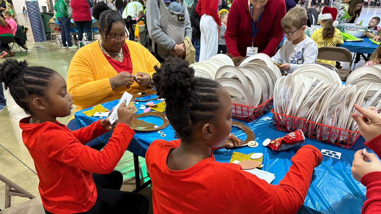 Courtney Dobson and her twin daughters, Brianna and Cecelia, making arts and crafts at the annual A Kid Again Holiday Adventure.