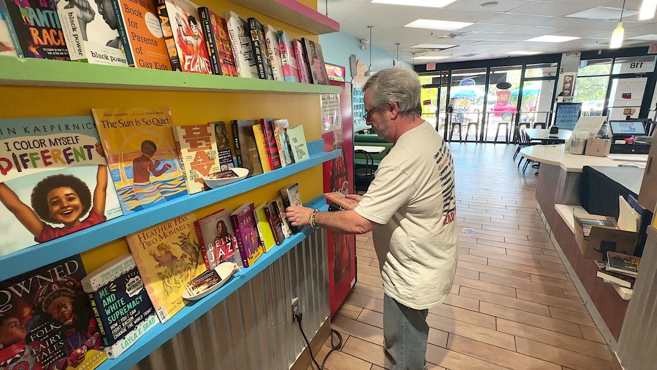 High school English teacher Adam Tritt sets up books banned from Brevard County schools' libraries at a local Ben & Jerry's ice cream shop so they are available for anyone who might want to read them. (Spectrum News/Randy Rauch)