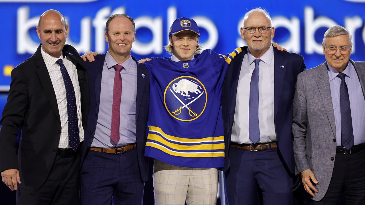 Konsta Helenius, center, poses after being selected by the Buffalo Sabres during the first round of the NHL hockey draft Friday, June 28, 2024, in Las Vegas. (AP Photo/Steve Marcus)