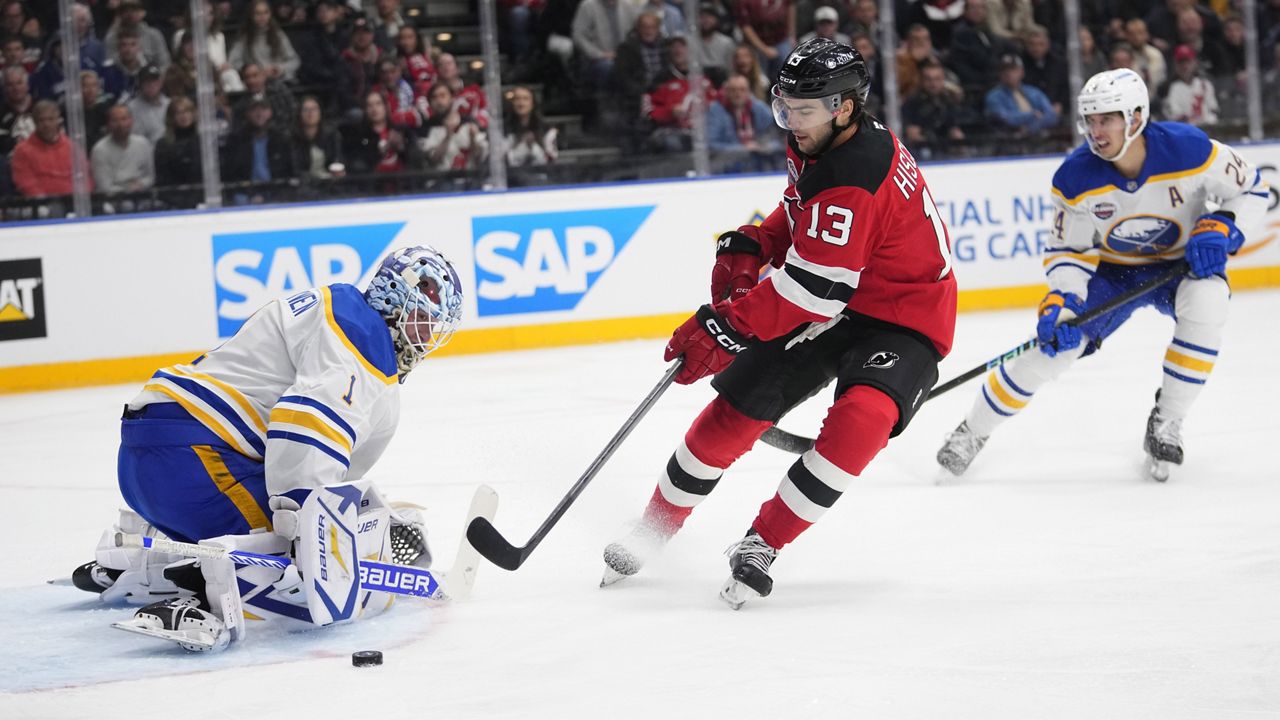 New Jersey Devils' Nico Hischier, centre, tries to score past Buffalo Sabres' goaltender Ukko-Pekka Luukkonen, left, during the NHL hockey game between Buffalo Sabres and New Jersey Devils, in Prague, Czech Republic, Friday, Oct. 4, 2024. (AP Photo/Petr David Josek)