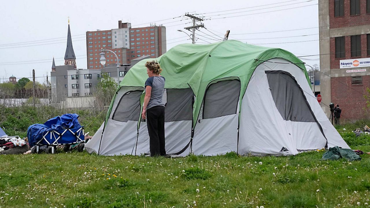 A woman stands near her tent at a homeless encampment before city workers arrived to clean up the area on May 16, in Portland. (Associated Press/Robert F. Bukaty, file)