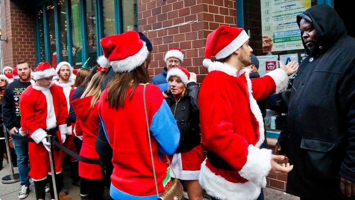 A SantaCon reveler attempts to argue his way past a bouncer and into a bar in 2016 in New York.