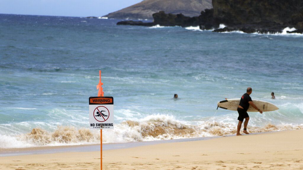 A surfer leaves the water in Honolulu, Saturday, July 25, 2020, as Hurricane Douglas approaches. (AP Photo/Caleb Jones)