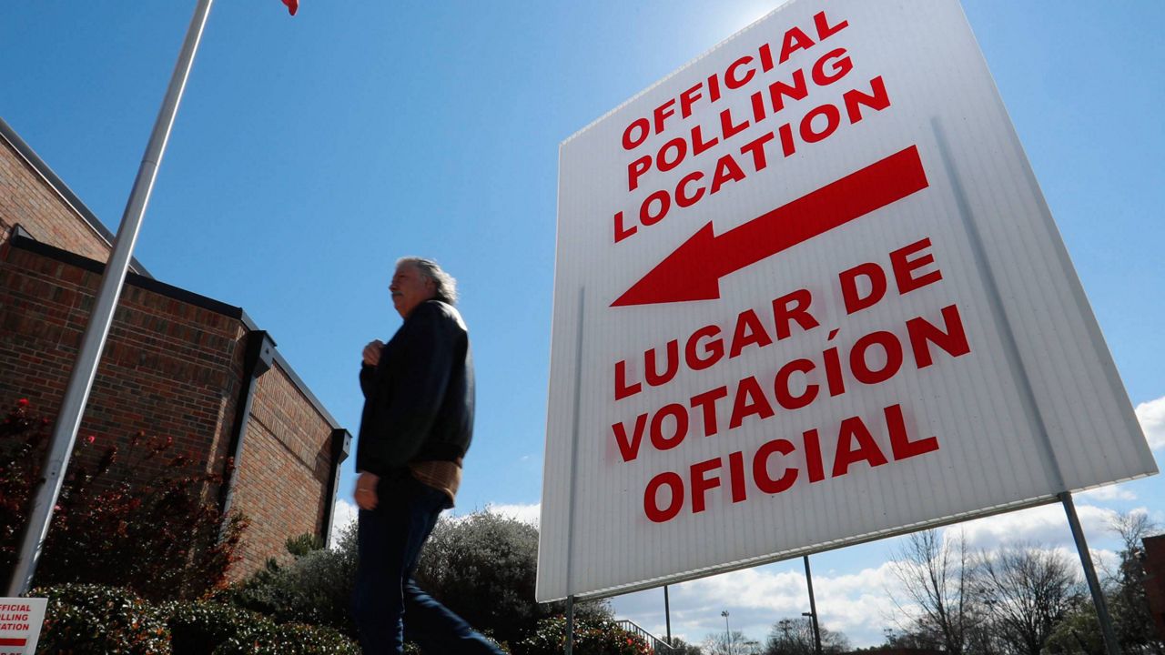 In this Feb. 26, 2020 file photo, using both the English and Spanish language, a sign points potential voters to an official polling location during early voting in Dallas. (AP Photo/LM Otero)