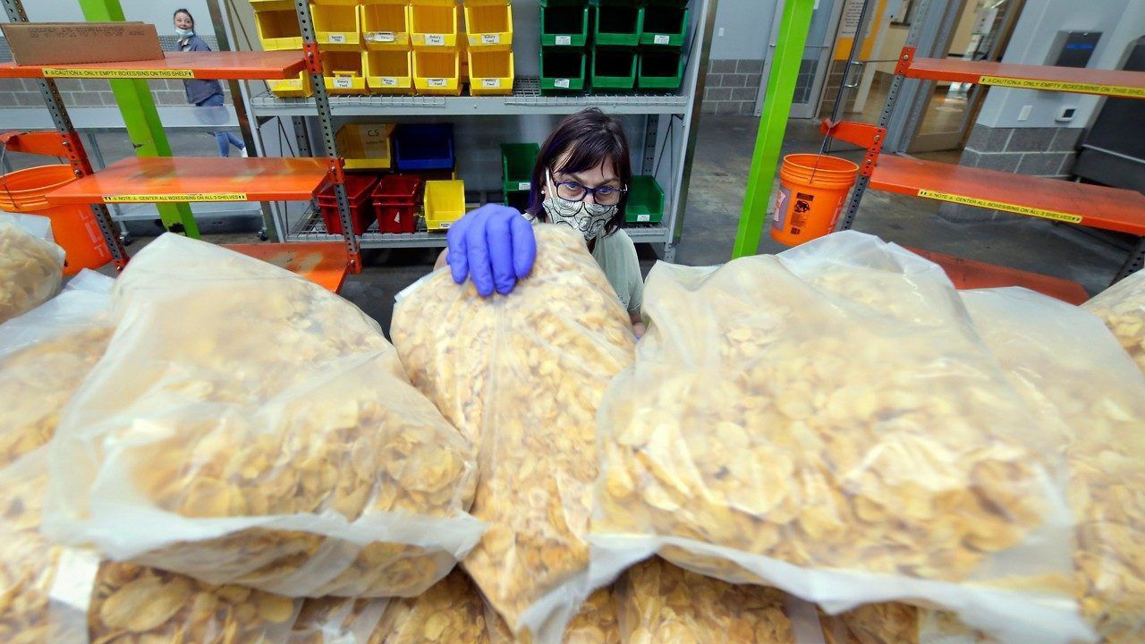 Volunteer Delia Swanner grabs individual bags of cereal to include into a grocery bag for a school student food program in the area known as 