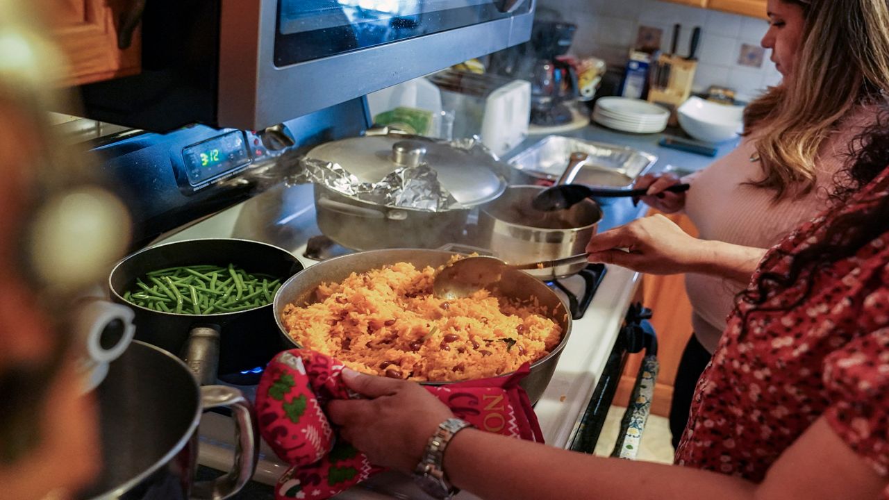 Vivian Zayas cooks rice and beans by her mother's recipe, the recently deceased Ana Martinez, as she and her sister Alexa prepare Thanksgiving dinner, Thursday, Nov. 26, 2020, in Deer Park, N.Y. Ana Martinez died at 78 on April 1 while recovering at a nursing home from a knee replacement.