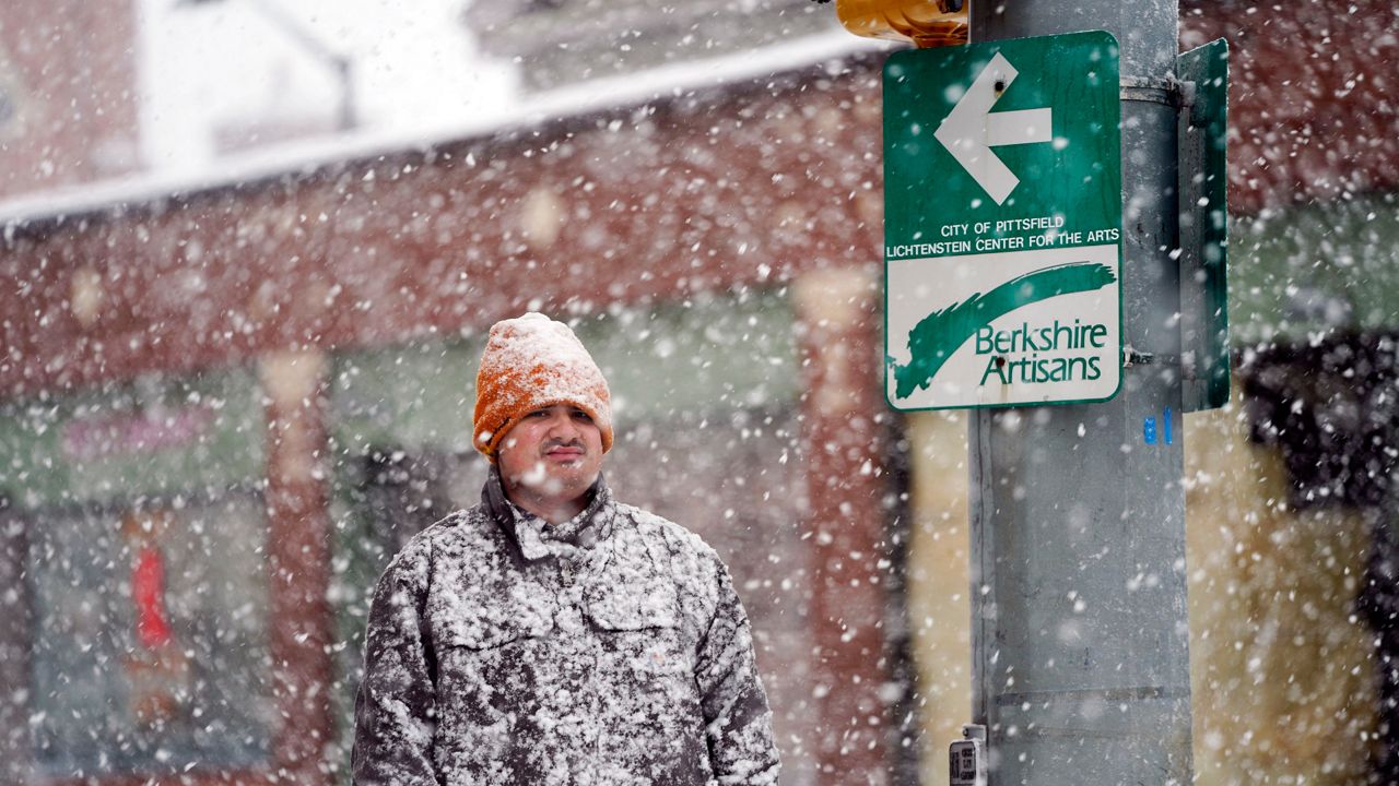 A man is covered in snow on Fenn Street in Pittsfield, Mass, Friday, Dec. 16, 2022. (Ben Garver/The Berkshire Eagle via AP)