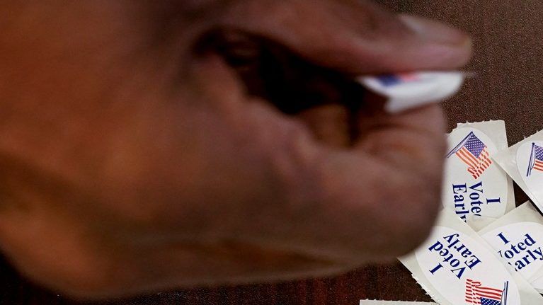 A voter takes a sticker after casting an early ballot at a polling station