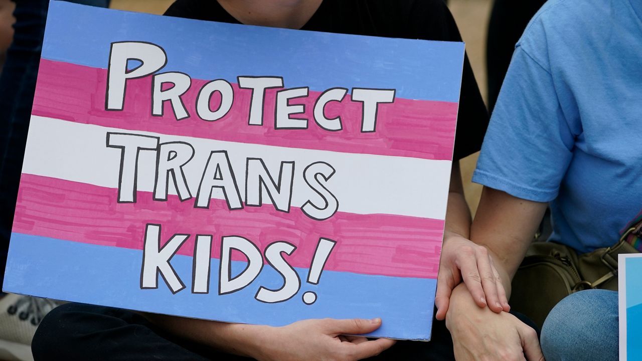 A protester holds a poster calling for lawmakers to protect trans children. (AP Photo/Rogelio V. Solis)