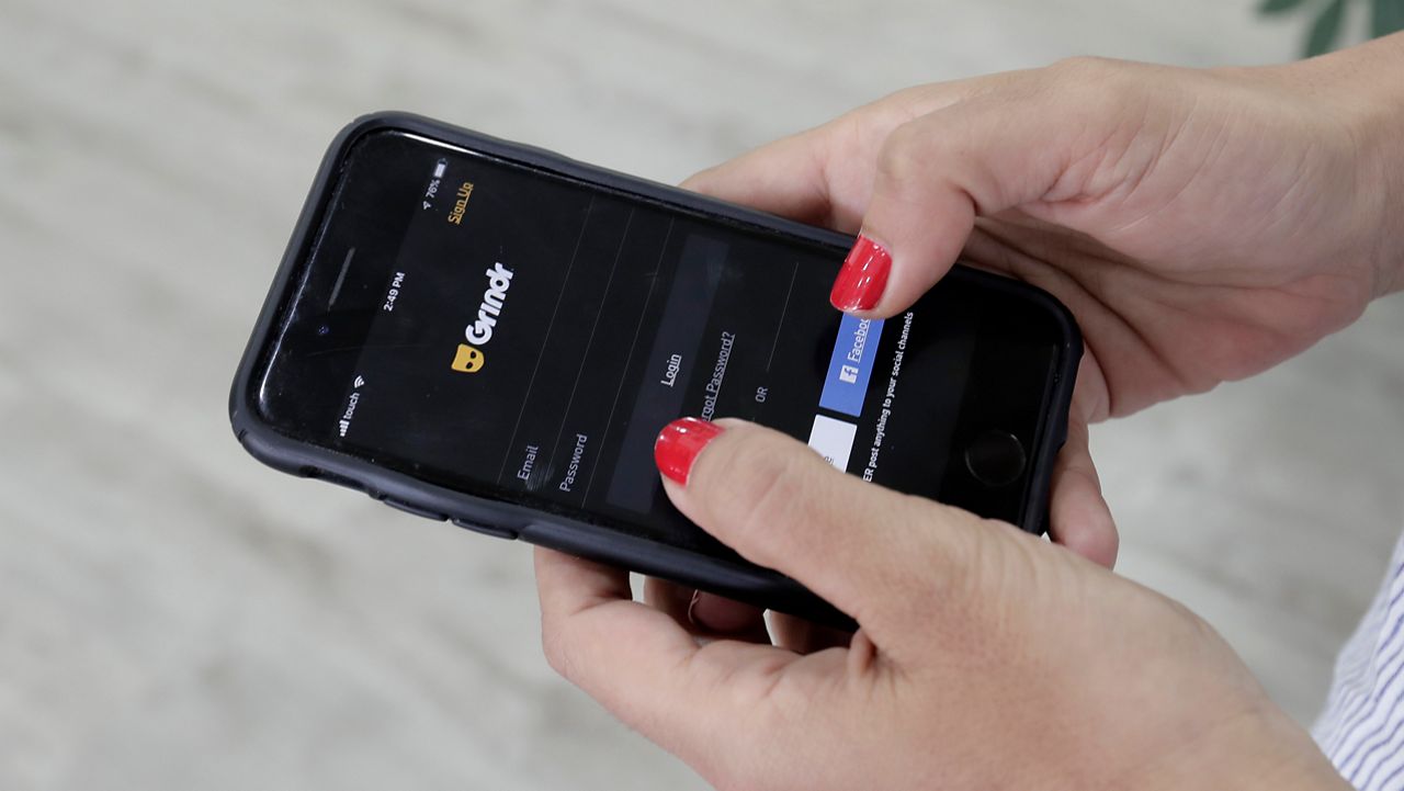 FILE - In this Wednesday, May 29, 2019, file photo, a person looks at the Grindr app on her mobile phone. (AP Photo/Hassan Ammar, File)