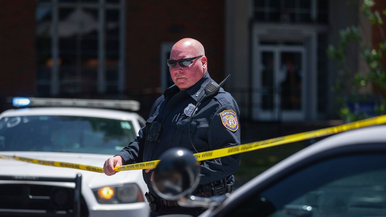 A Memphis Police officer extends crime scene tape around the perimeter of an active shooter situation near the University of Memphis, Tuesday, May 2, 2023. (Patrick Lantrip/Daily Memphian via AP)