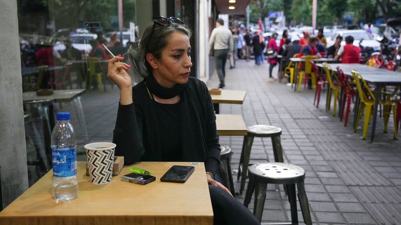 A woman sits in the alfresco dining area of a cafe at Tajrish commercial district without wearing her mandatory Islamic headscarf in northern Tehran, Iran, Saturday, April 29, 2023. 