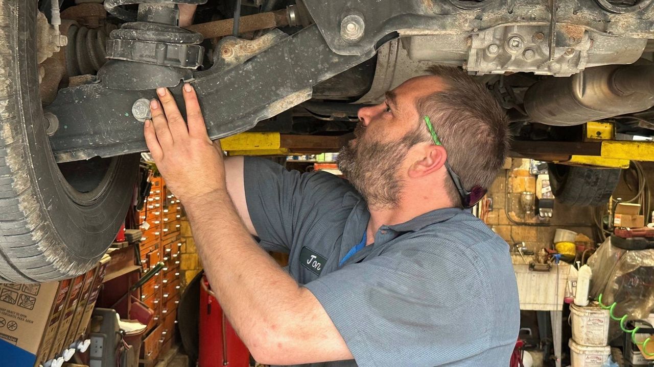 Mechanic Jon Guthrie inspects the underside of a 2014 Honda Ridgeline pickup truck at Japanese Auto Professional Service in Ann Arbor, Michigan. People are keeping their vehicles longer due to shortages of new ones and high prices. That drove the average U.S. vehicle age up to a record 12.5 years in 2023, according to S&P Global Mobility. (AP Photo/Tom Krisher)
