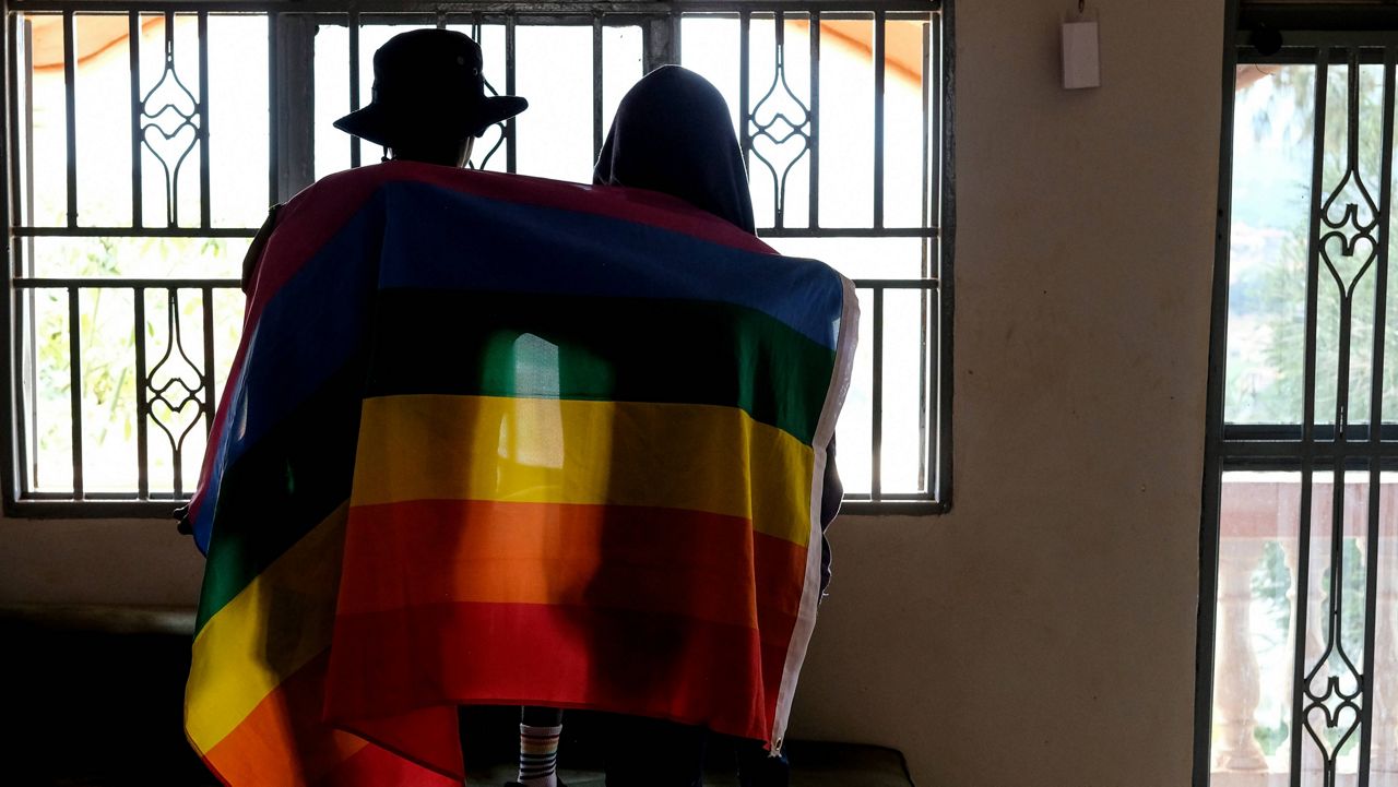 A gay Ugandan couple cover themselves with a pride flag as they pose for a photograph in Uganda on March 25, 2023. Uganda's president Yoweri Museveni has signed into law tough new anti-gay legislation supported by many in the country but widely condemned by rights activists and others abroad, it was announced Monday, May 29, 2023. (AP Photo)