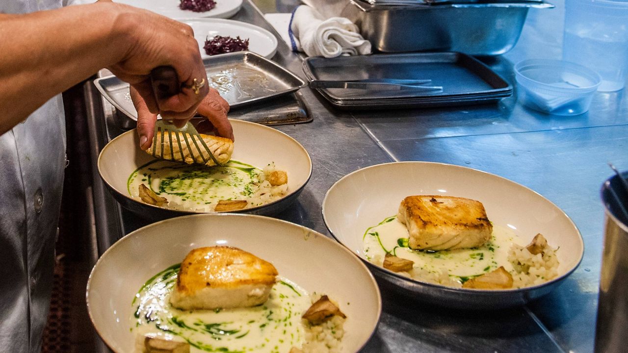 A worker arranges food onto plates in the kitchen of a restaurant in New York on Dec. 14, 2021. Food workers who showed up while sick or contagious were linked to about 40% of restaurant food poisoning outbreaks with a known cause between 2017 and 2019, federal health officials said Tuesday, May 30, 2023. (AP Photo/Brittainy Newman)