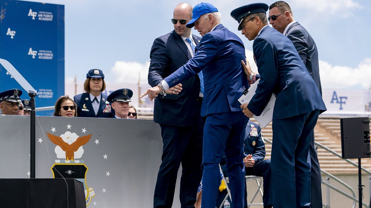 President Joe Biden points to sandbags after falling on stage during the 2023 United States Air Force Academy Graduation Ceremony at Falcon Stadium, Thursday, June 1, 2023, at the United States Air Force Academy in Colorado Springs, Colo. (AP Photo/Andrew Harnik)