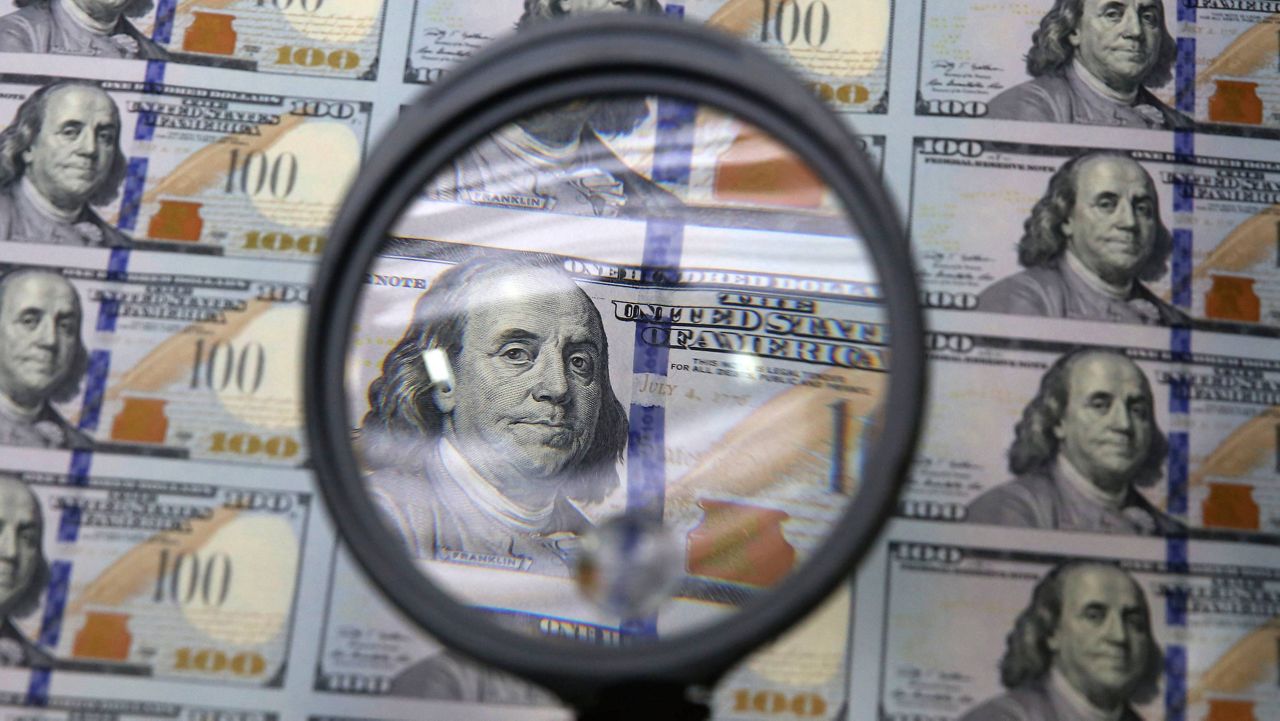 A sheet of uncut $100 bills is inspected during the printing process at the Bureau of Engraving and Printing Western Currency Facility in Fort Worth, Texas, on Sept. 24, 2013. More than $200 billion may have been stolen from two large pandemic-relief initiatives, according to a new estimates from a federal watchdog investigating federally funded programs designed to help small businesses survive the worst public health crisis in more than a hundred years. (AP Photo/LM Otero)