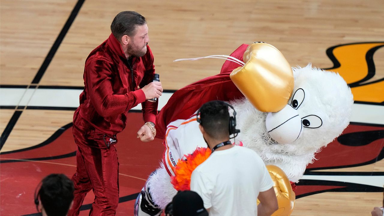 Former MMA fighter Conor McGregor punches Burnie, the Miami Heat mascot, during a break in Game 4 of the basketball NBA Finals against the Denver Nuggets, Friday, June 9, 2023, in Miami. The man who occupies Burnie's costume needed medical attention. (AP Photo/Lynne Sladky)