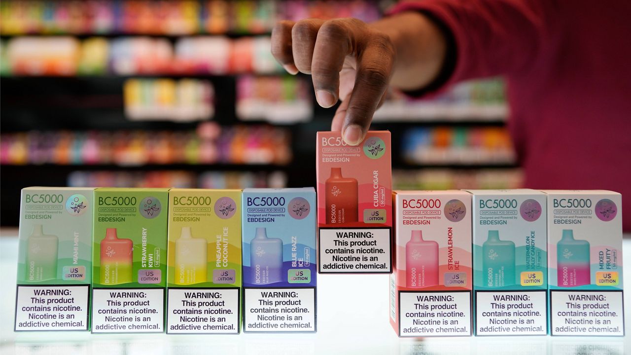 An employee displays some of the varieties of disposable electronic cigarette devices manufactured by EB Design, formerly known as Elf Bar, at Vapes N Smoke in Pinecrest, Fla., Monday, June 26, 2023. (AP Photo/Rebecca Blackwell)