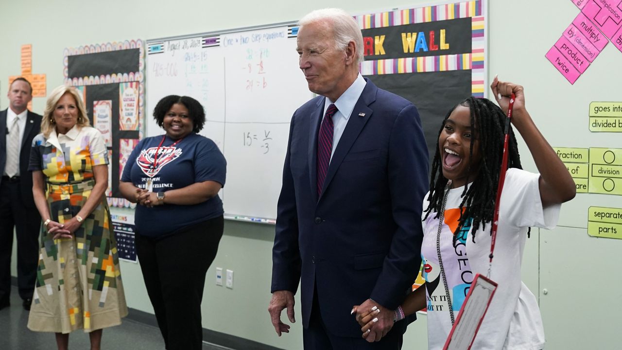 President Joe Biden holds hands with a student at Eliot-Hine Middle School on Monday, Aug. 28, 2023, in Washington as he visits the school, located east of the U.S. Capitol, to mark the District of Columbia's first day of school for the 2023-24 year. First lady Jill Biden looks on at left. (AP Photo/Manuel Balce Ceneta)