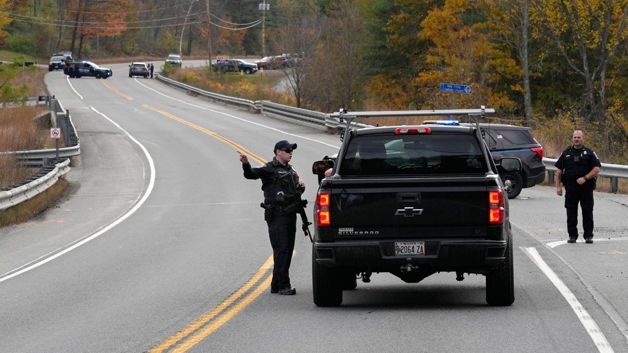 Police officers speak with a motorist at a roadblock, Thursday, Oct. 26, 2023, in Lisbon, Maine, during a manhunt for the suspect of Wednesday's mass shootings. The shootings took place at a restaurant and bowling alley in nearby Lewiston, Maine. (AP Photo/Robert F. Bukaty)