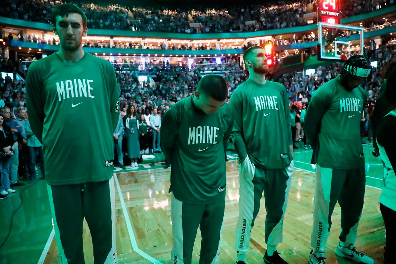 The Boston Celtics stand for a moment of silence for the victims of the shootings in Lewiston, Maine, before the team's NBA basketball game against the Miami Heat, Friday, Oct. 27, 2023, in Boston. (AP Photo/Michael Dwyer)