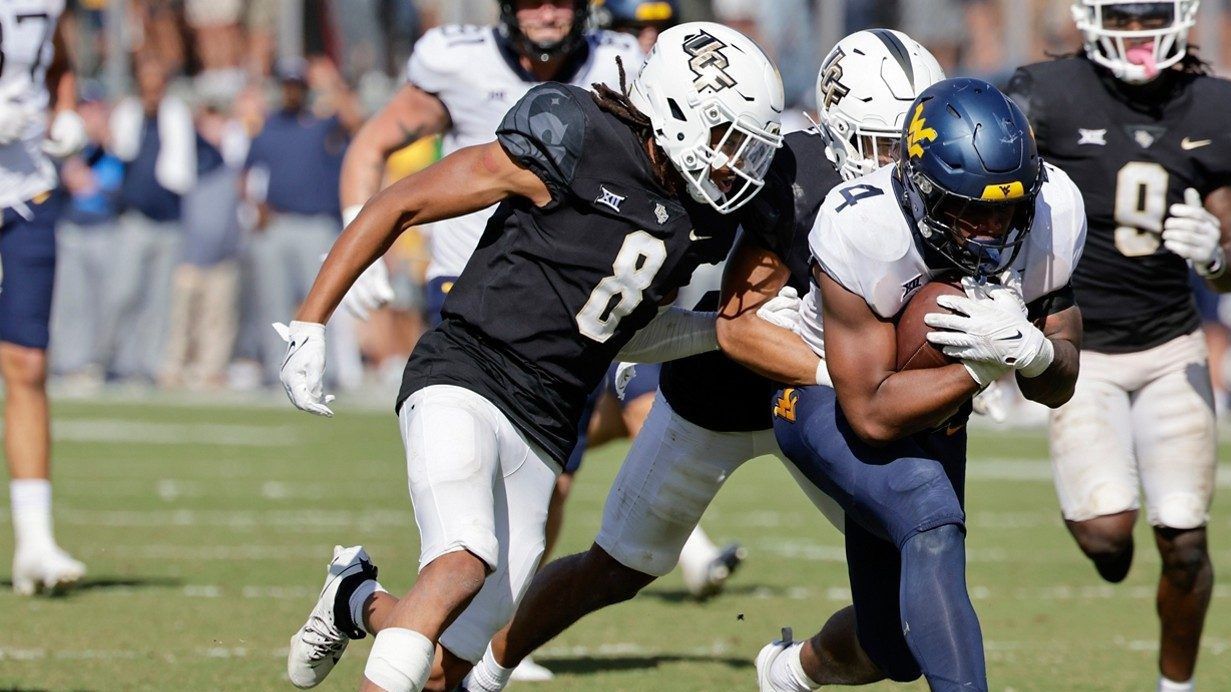 West Virginia running back CJ Donaldson Jr., right is tackled by Central Florida defensive backs Demari Henderson, left, and Nikai Martinez, behind, during the second half of an NCAA college football game, Saturday, Oct. 28, 2023, in Orlando, Fla. (AP Photo/Kevin Kolczynski)