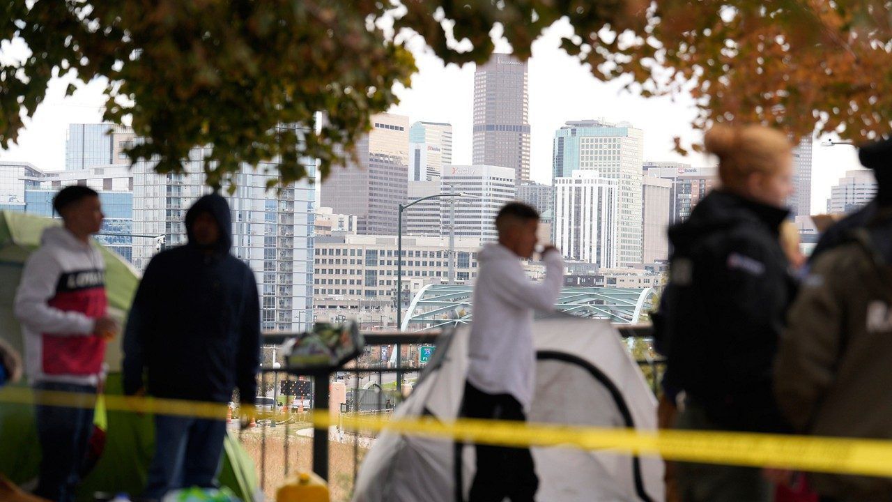 Occupants wait to see how police officers work during a city-sponsored sweep of an encampment overlooking the city skyline on Diamond Hill on Wednesday, Nov. 1, 2023 in Denver.
