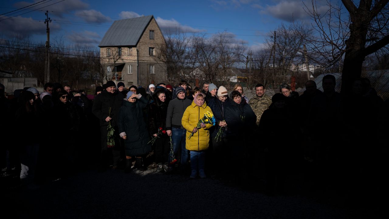 People pay respect as the coffin containing the body of Serhii Havryliuk passes by during his funeral procession in Tarasivka village on Wednesday, Feb. 15, 2023.