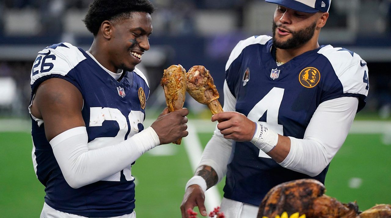 Dallas Cowboys cornerback DaRon Bland, left, and quarterback Dak Prescott celebrate by eating Thanksgiving turkey legs