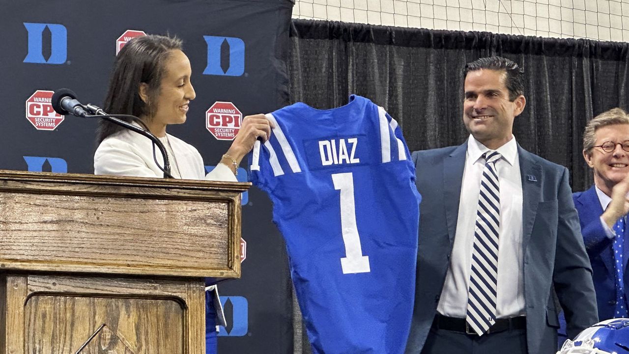 New Duke head football coach Manny Diaz, middle, holds a jersey with Duke athletic director Nina King, left, as Duke president Vincent Price looks on Saturday, Dec. 9, 2023, in Durham, N.C. Duke announced Diaz's hiring on Thursday night, capping a 10-day search. (AP Photo/Aaron Beard)