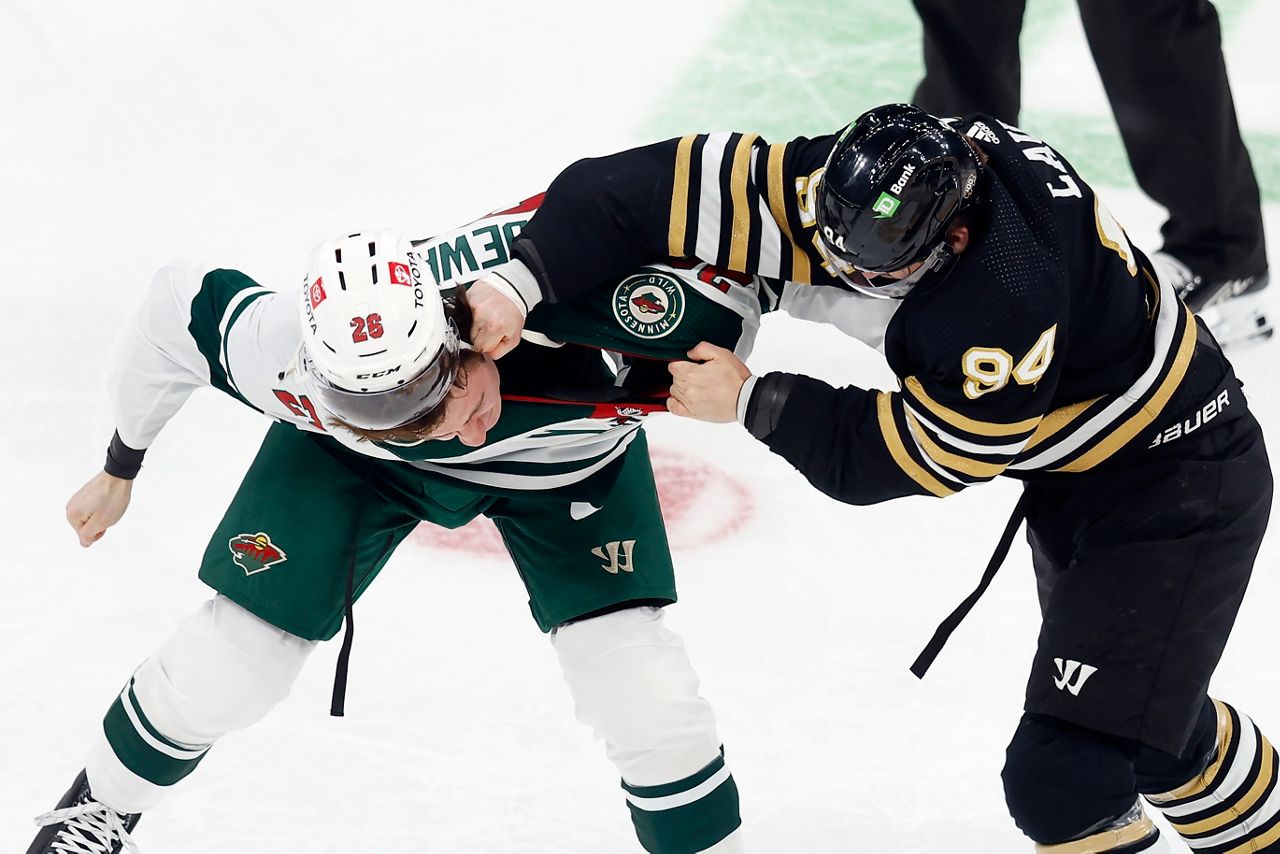 Boston Bruins' Jakub Lauko (94) and Minnesota Wild's Connor Dewar (26) fight during the first period of an NHL hockey game, Tuesday, Dec. 19, 2023, in Boston. (AP Photo/Michael Dwyer)
