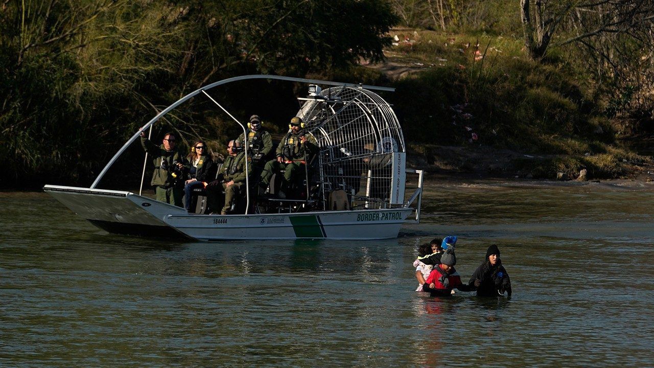 Border patrol agents watch as migrants cross the Rio Grande at the Texas-Mexico border, Wednesday, Jan. 3, 2024, in Eagle Pass, Texas. (AP Photo/Eric Gay)