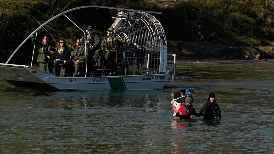 Border patrol agents watch as migrants cross the Rio Grande at the Texas-Mexico border, Wednesday, Jan. 3, 2024, in Eagle Pass, Texas. (AP Photo/Eric Gay)