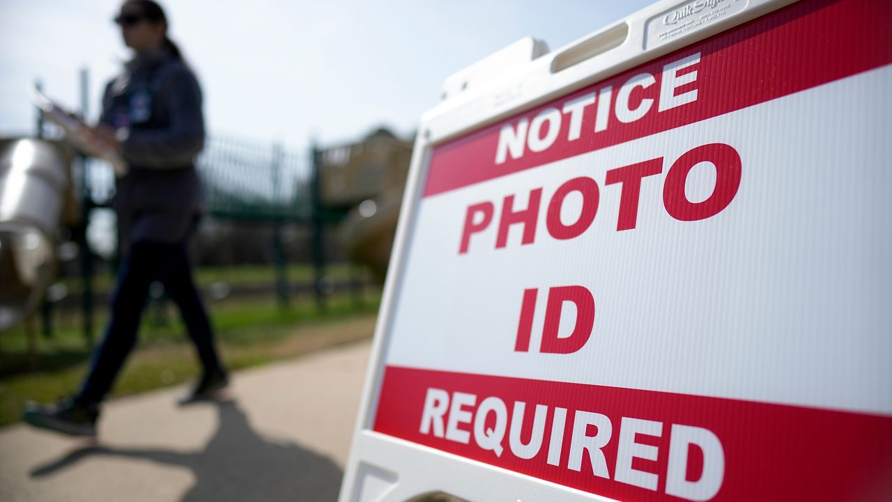 A Super Tuesday voter walks past a sign requiring a photo ID at a polling location Tuesday, March 5, 2024, in Mount Holly, N.C. (AP Photo/Chris Carlson)