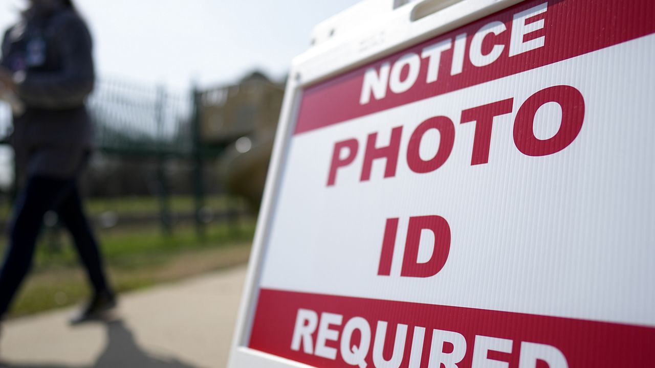 A Super Tuesday voter walks past a sign requiring a photo ID at a polling location Tuesday, March 5, 2024, in Mount Holly, N.C. (AP Photo/Chris Carlson)