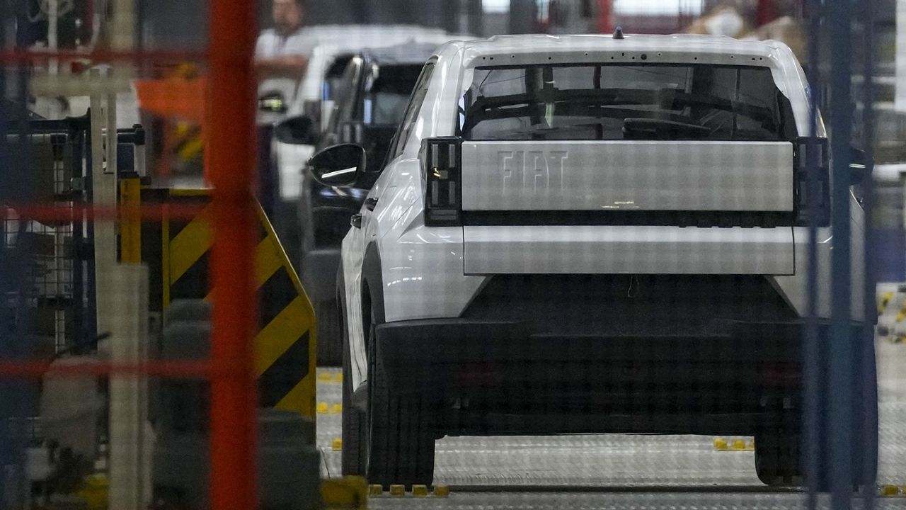 A factory worker stands by all-new Fiat Grande Panda electric vehicles in the assembly hall in the Stellantis factory, in Kragujevac, Serbia, Monday, July 22, 2024. (AP Photo/Darko Vojinovic, File)