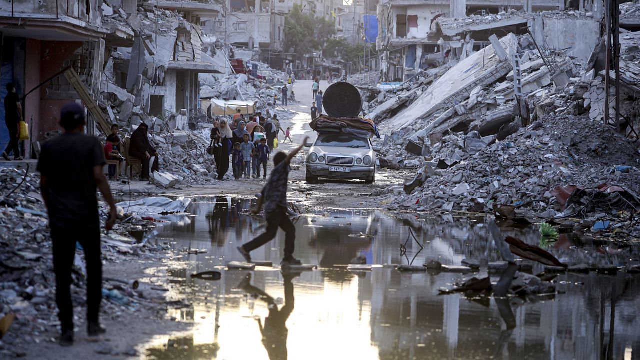 Palestinians displaced by the Israeli air and ground offensive on the Gaza Strip, walk past sewage flowing into the streets of the southern town of Khan Younis, Gaza Strip, on July 4, 2024. (AP Photo/Jehad Alshrafi, File)