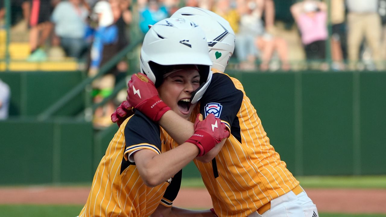 Lake Mary, Fla.'s Hunter Alexander, left, is hugged by Chase Anderson, right, after Alexander's bunt single allowed the winning run to score from second base Taiwan to win the game during the eighth inning of the the Little League World Series Championship game in South Williamsport, Pa., Sunday, Aug. 25, 2024. (AP Photo/Tom E. Puskar)